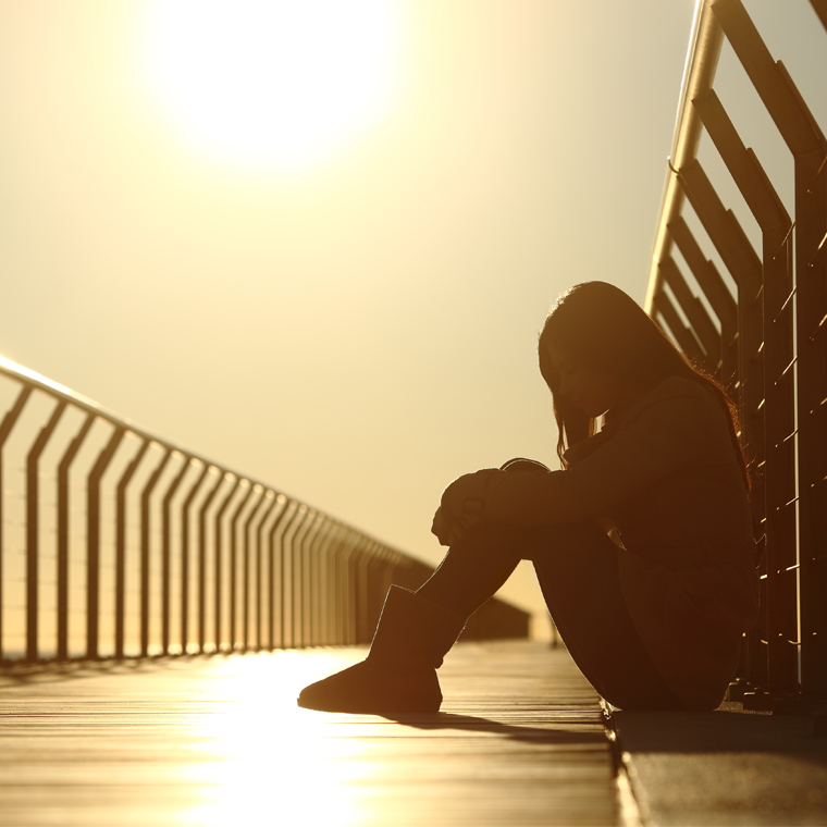 depressed teen on bridge at sunset