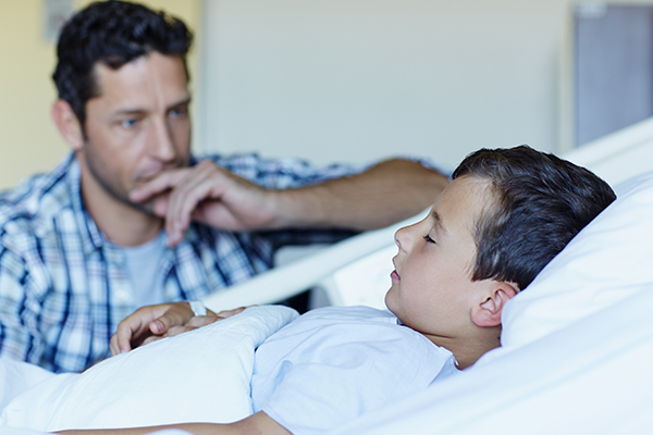 Boy in hospital bed with father nearby